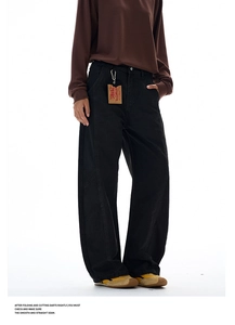 Detail of curved seam black wide-leg trousers with vintage leather tag and retro sneakers