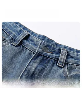 Close-up of the waist structure of washed blue straight denim jeans with a metal button