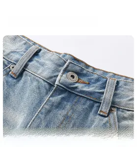Detailed macro view of the light blue denim jeans waistband and silver embossed button