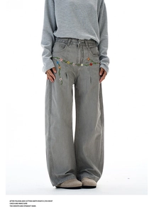 Detail view of colorful floral embroidery on high-waist grey wide-leg work pants