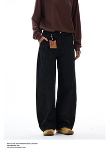 Detailed view of black wide-leg trousers with curved seam design and vintage hangtag