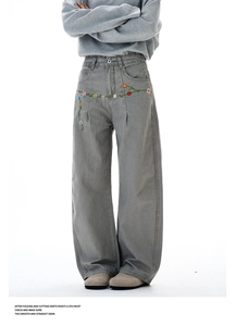 Detail view of colorful floral embroidery on high street grey wide-leg trousers