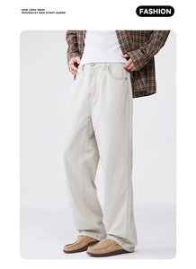 Detailed view of beige loose-fit trousers with brown topstitch and twill fabric texture