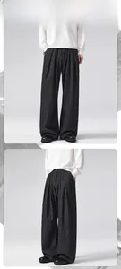 Close-up of pleated dark pinstripe wide-leg trousers with vertical stripe texture