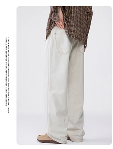 Detailed side view of off-white loose-fit trousers featuring contrast yellow stitching