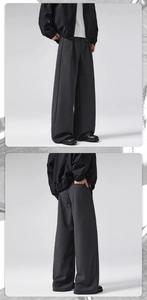 Detailed close-up showing the pleated front and texture of men's charcoal wool trousers