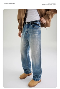 Detail view of light blue wash straight-leg denim jeans with vintage whiskers and distressed finish