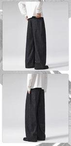 Detail showing the dark grey pinstripe fabric texture and relaxed wide leg fit on the model