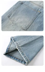 Detail view of light blue jeans showing the back pocket stitching and raw hem leg opening