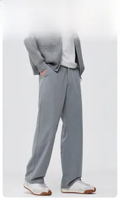 Detail of light gray wide-leg trousers featuring a loose fit and premium draped fabric texture