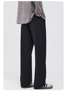 Macro detail of black men's wide-leg trousers showing premium draped fabric texture