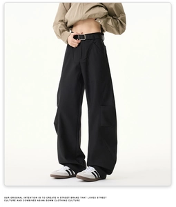 Détail du pantalon large noir avec design plissé et ceinture en cuir