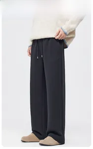 Detail of men's black wide-leg trousers with elastic drawstring waist and straight drape