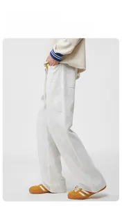 Détail du pantalon de jogging évasé gris clair montrant la coupe ample et la texture du tissu