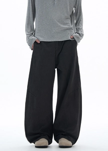 Detail view of black wide-leg trousers featuring curved seams and high-drape fabric