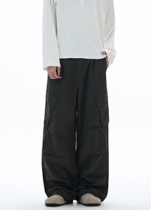 Dettaglio dei pantaloni cargo verde scuro con tasche laterali e taglio ampio dritto