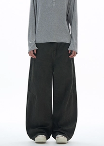 Close-up of baggy dark grey cargo pants featuring curved knee seam and cotton twill texture