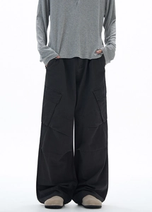Dettaglio dei pantaloni cargo neri larghi con grandi tasche a patta e silhouette ampia