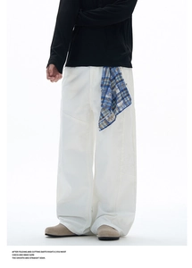 Détail d'un jean blanc à jambe large avec un tissu à carreaux bleu attaché à la taille