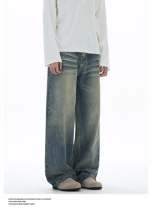 Detail of vintage washed wide-leg jeans featuring cat-whisker texture and faded blue finish