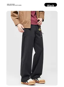 Detail of men's loose wide-leg trousers in black with premium draped fabric texture