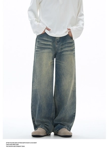Detail of vintage yellow-wash wide-leg denim jeans with unique cat-whisker texture