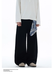 Détail d'un pantalon large noir avec une poche à carreaux bleu et orange décorative