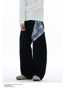 Détail du pantalon large noir avec une pièce décorative en tissu écossais à carreaux