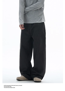 Detail view of men's black wide-leg trousers with unique diagonal stitching and loose cut