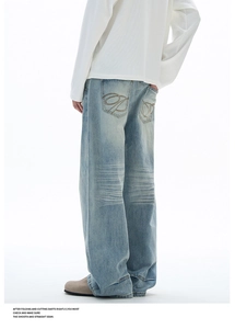 Détail du jean bleu clair avec broderie de poche incurvée et texture délavée denim