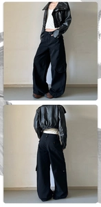 Detail view of black baggy cargo pants and cropped faux leather jacket in street style