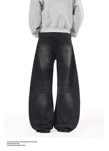 Macro detail of oversized washed black denim jeans featuring back pockets and street style texture