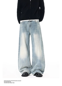 Detail of light blue washed denim jeans featuring distressed texture and loose fit legs