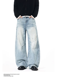 Detail of light blue distressed wide-leg jeans with vintage wash and curved seam design