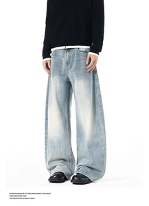 Detailed view of light blue washed denim jeans with heavy distress and loose curved fit