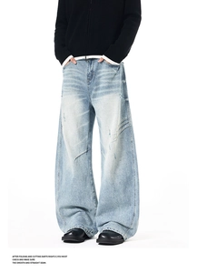 Detail of light blue wide-leg jeans with distressed holes and vintage washed finish