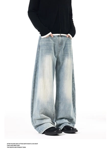 Detail of light blue washed denim jeans featuring vintage whiskers and stacked leg cuffs