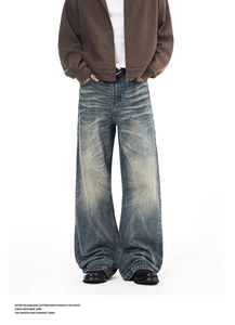 Detail of vintage blue washed loose fit jeans with distressed whiskers and wide leg cut