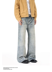 Detailed view of light blue washed denim jeans with distressed whiskers and vintage texture