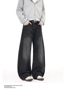 Detail of loose fit black washed jeans with vertical texture and metal buckle belt
