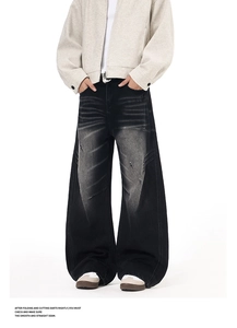 Detail of charcoal black washed jeans featuring distressed pleated seams and baggy silhouette