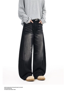 Close-up of baggy black washed denim jeans featuring vintage whiskers and wide-leg cut