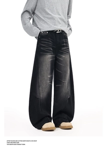 Detail view of washed denim whiskers and stitching on vintage black wide-leg jeans