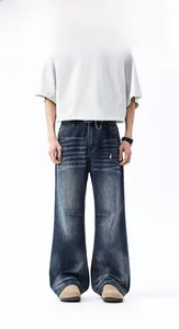 Dettaglio di jeans baggy blu con trama baffata, taglio a gamba larga e catena in metallo