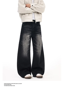 Detail of distressed black washed denim jeans featuring pleated scratching and ripped holes