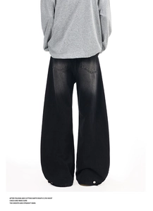 Detail view of washed black wide-leg jeans with vintage fading and back pocket design