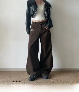 Detail of star-shaped metal rivets on brown straight-leg cotton trousers pockets