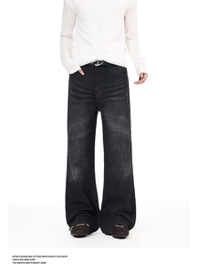 Detail shot of vintage washed cat-whisker texture on black flared denim jeans with metal buckle