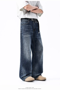 Dettaglio dei jeans larghi blu lavato vintage con baffi e cintura in pelle intrecciata