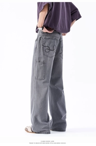 Dettaglio dei pantaloni cargo grigi a gamba larga con tasche e ricamo a onde sul retro